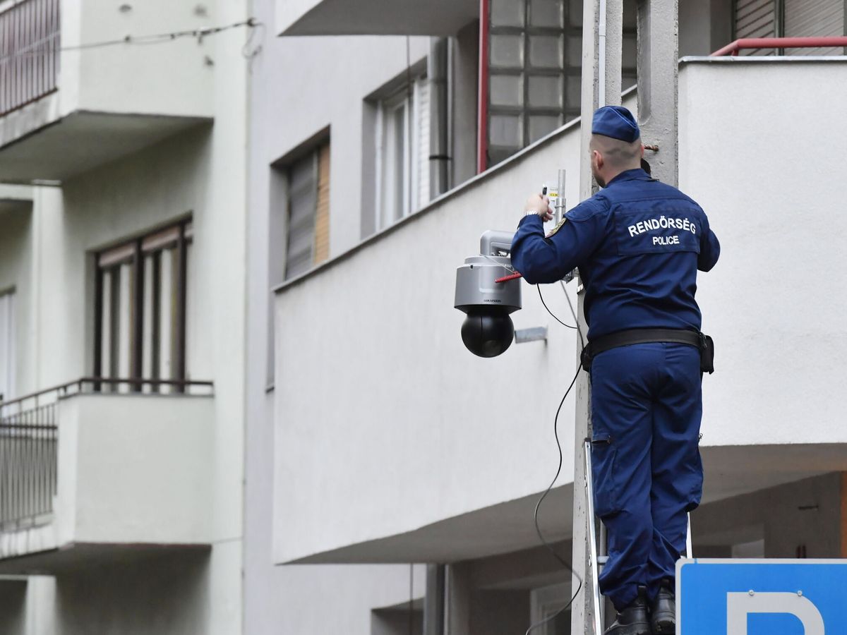 Foto: Un agente de policía húngaro coloca una cámara de vigilancia en un poste en Budapest (EFE/Lakatos Peter)