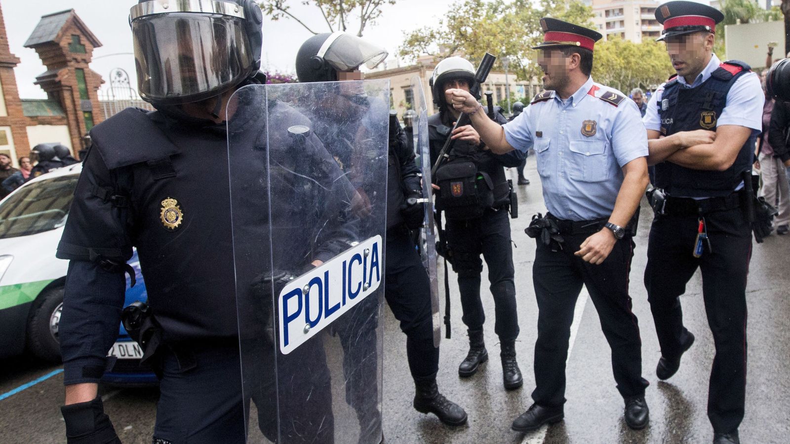 Foto: Agentes antidisturbios de la Policía Nacional y de los Mossos d' Esquadra discuten frente a un instituto. (EFE)