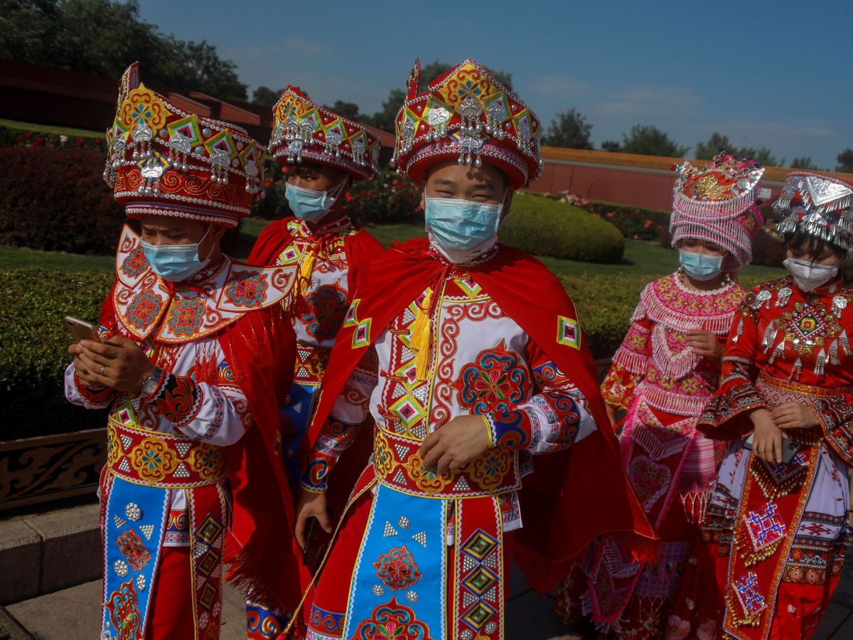 Foto:  Visitantes de la etnia Miao visten con trajes tradicionales mientras se protegen con mascarillas en Tiananmen en China, Pekín. (EFE)