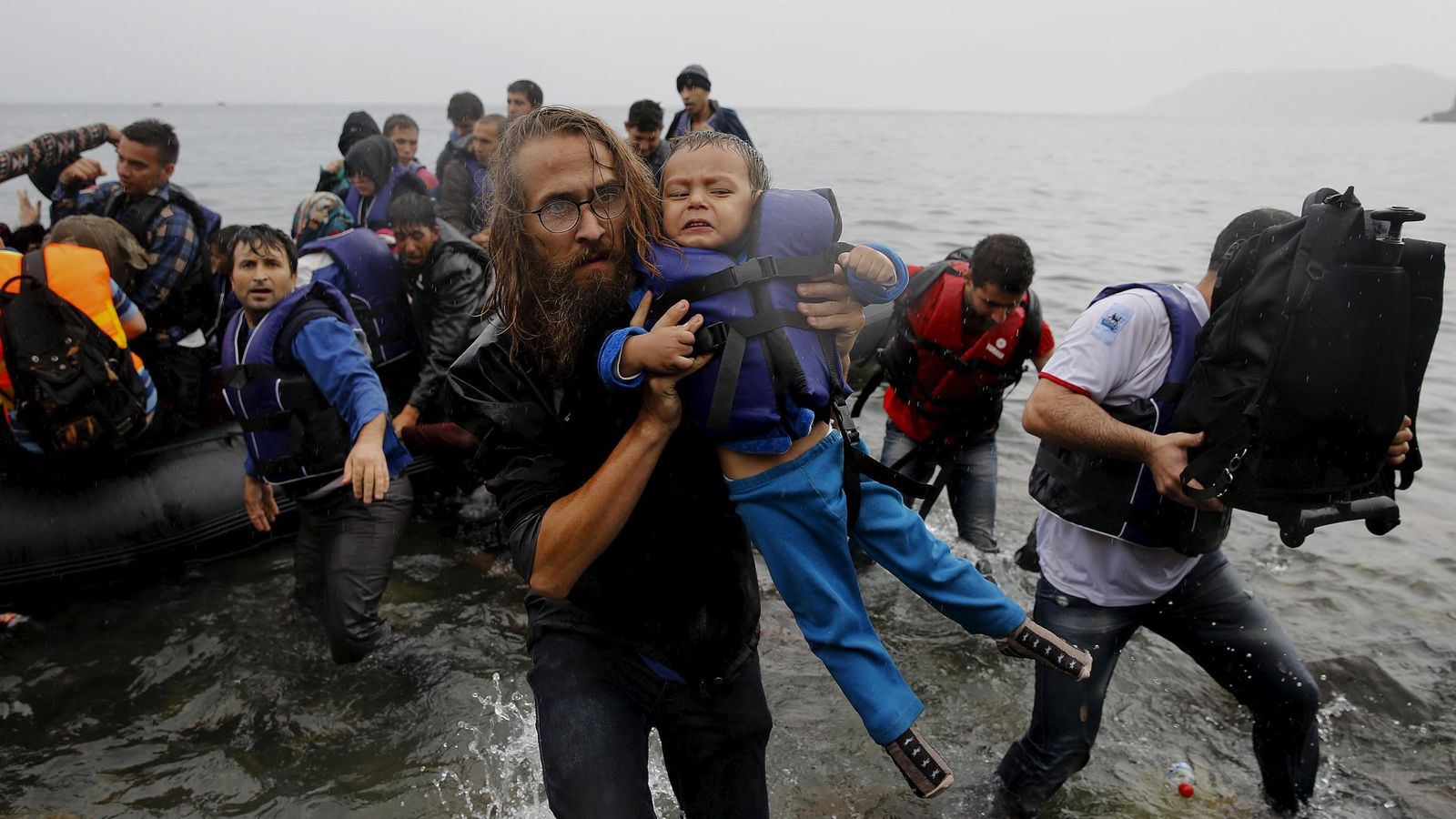 Foto: Un voluntario ayuda a un niño refugiado sirio a llegar a tierra en la isla de Lesbos, el 23 de septiembre de 2015 (Reuters)