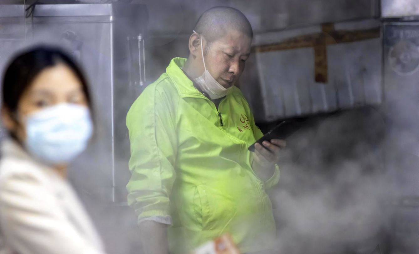 Un hombre con mascarilla prepara comida en un puesto callejero de Guangzhou, China. (Reuters)
