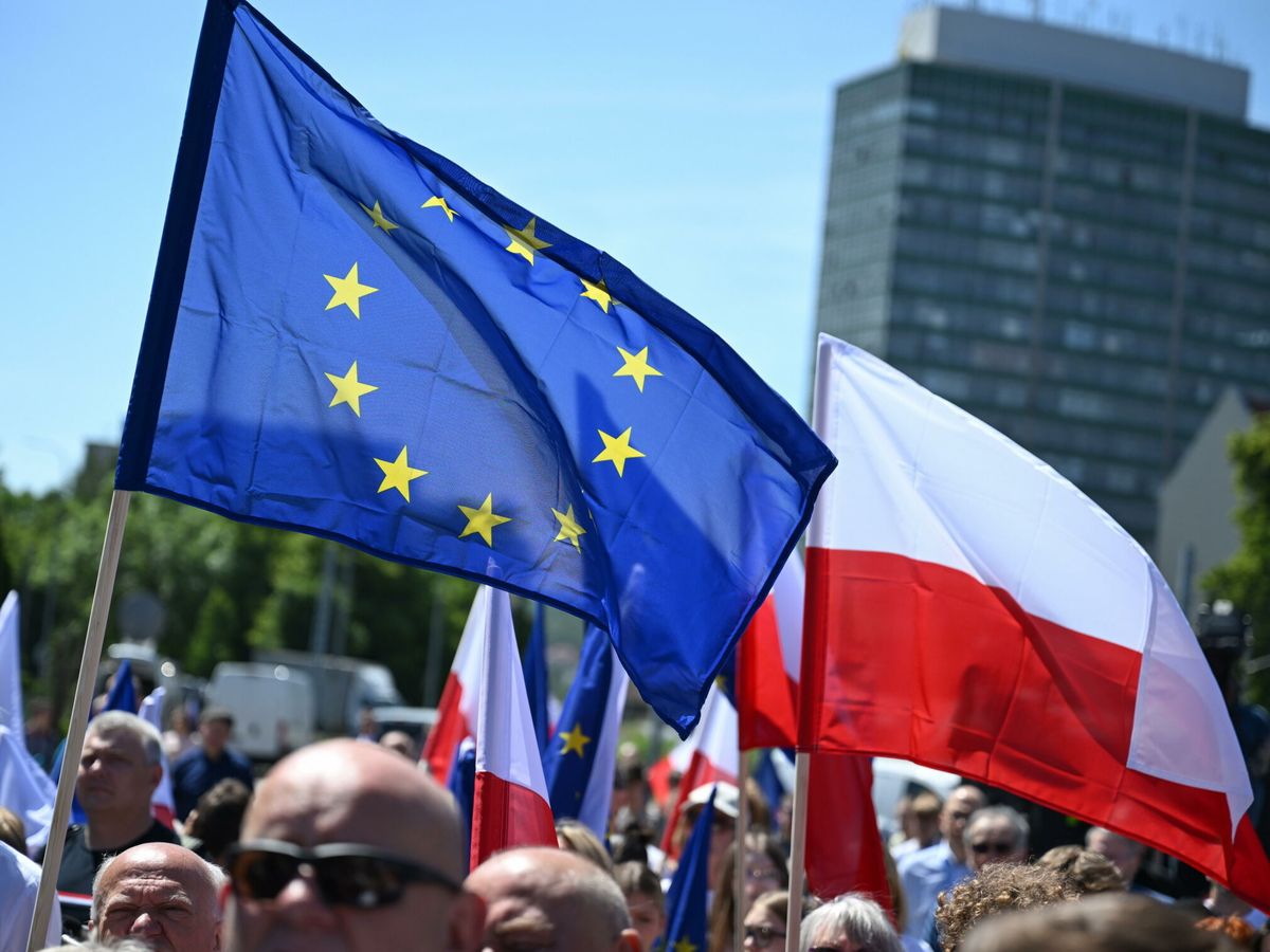 Foto: Un grupo de personas ondea la bandera polaca y una bandera de la Unión Europea en una ceremonia conmemorativa del 35º aniversario de la Unión Europea (EFE EPA/Adam Warzawa)