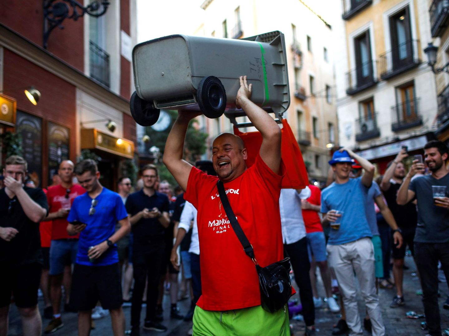 Un seguidor del Liverpool carga con un cubo de basura en una calle de Madrid. (EFE)