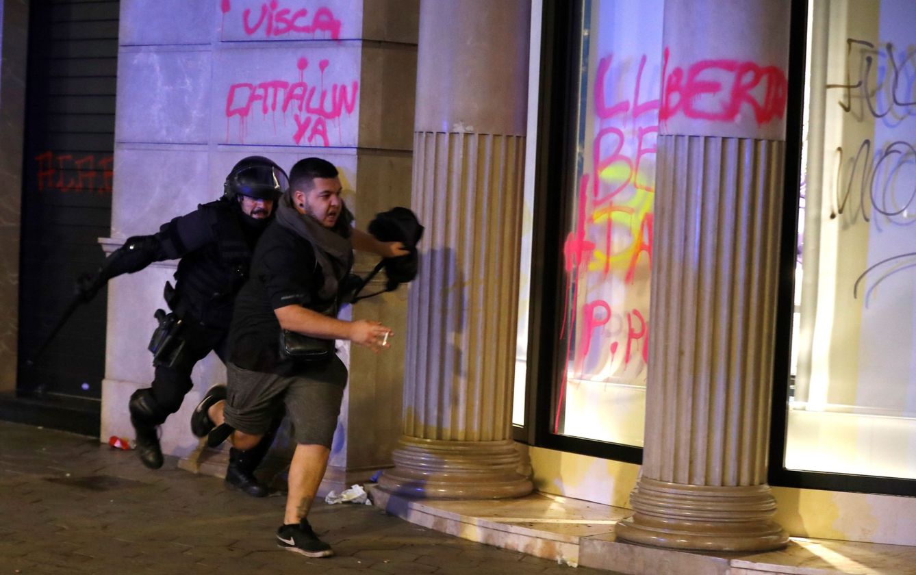 Un miembro de los Mossos d'Esquadra corre tras un manifestante. (EFE)