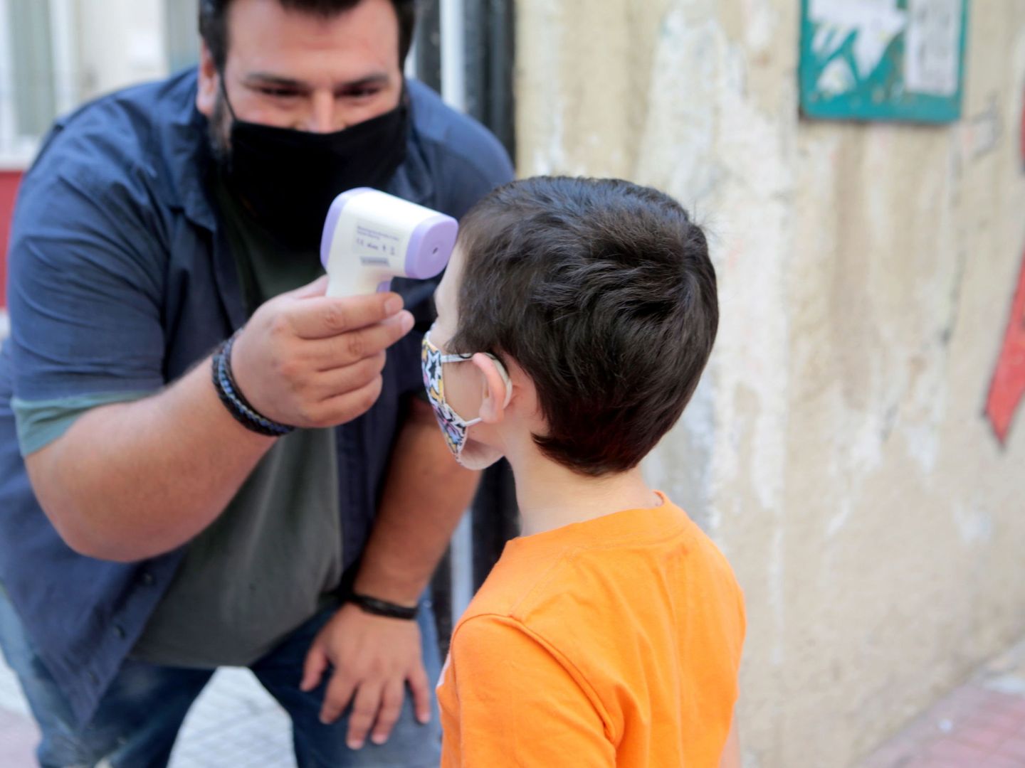 Un profesor mide la temperatura de un niño para entrar en un colegio en Atenas. (EFE)