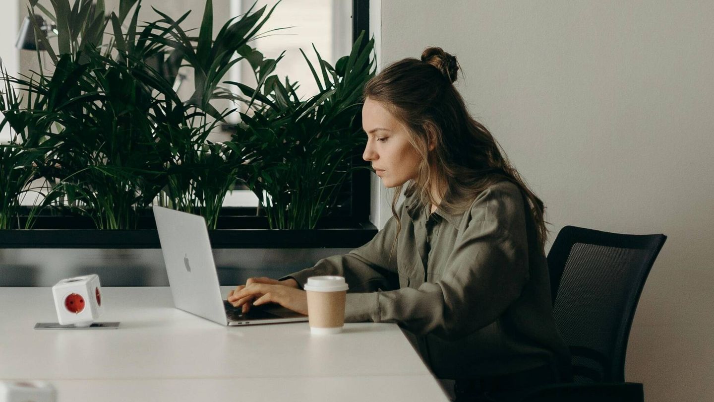 Una joven revisa su ordenador en una oficina. (Pexels)
