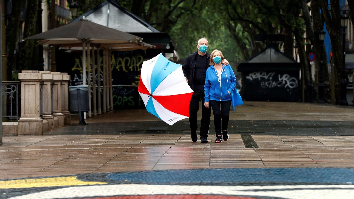 Una pareja protegida con su mascarilla pasea por las Ramblas, en Barcelona. (EFE)