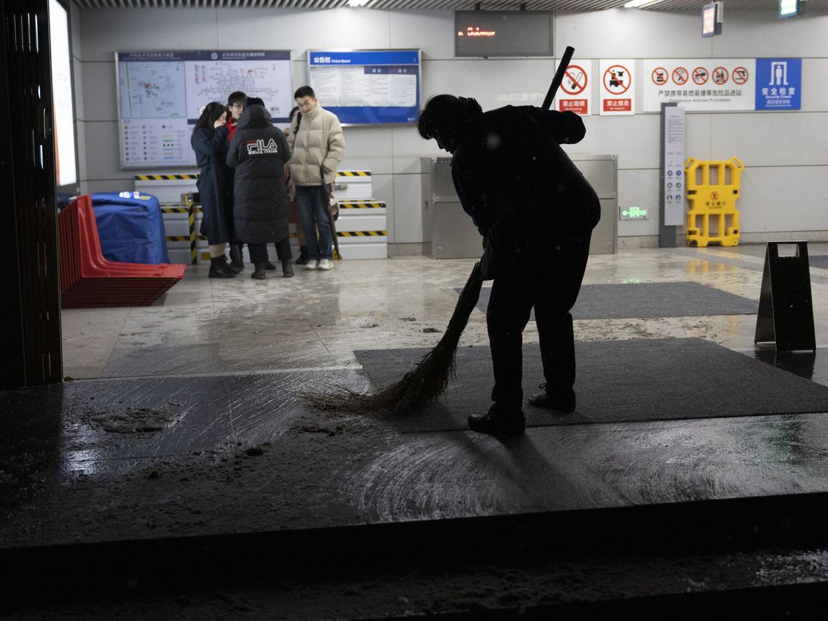 Foto: Un hombre limpia la entrada de una estación de Metro en Pekín tras el temporal de nieve. (EFE/Andrés Martínez Casares)
