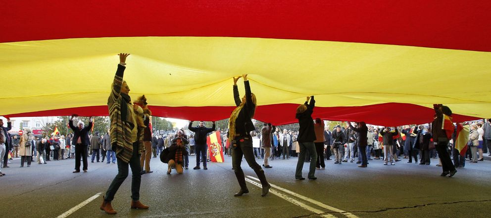 Varias personas sostienen una bandera española durante su participación en la concentración. (EFE)