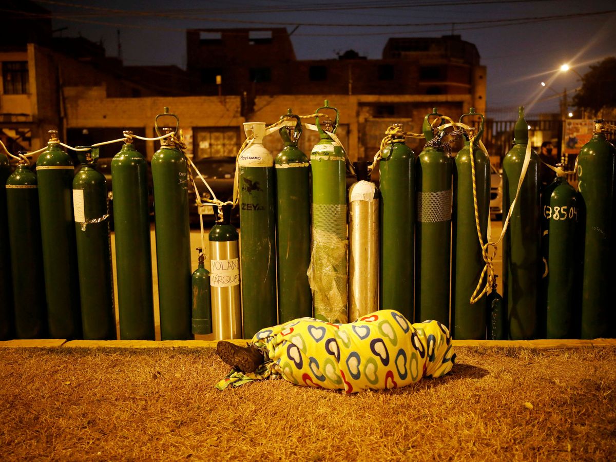 Foto: Una persona duerme frente a un punto de relleno de tanques de oxígeno, en Callao, Perú. (Reuters)