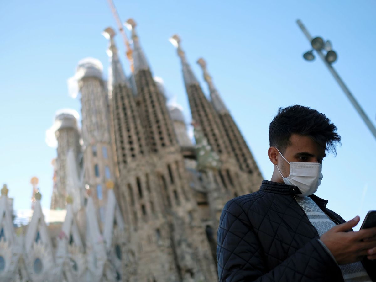 Foto: Un joven porta una mascarilla frente a la Sagrada Familia. (Reuters)