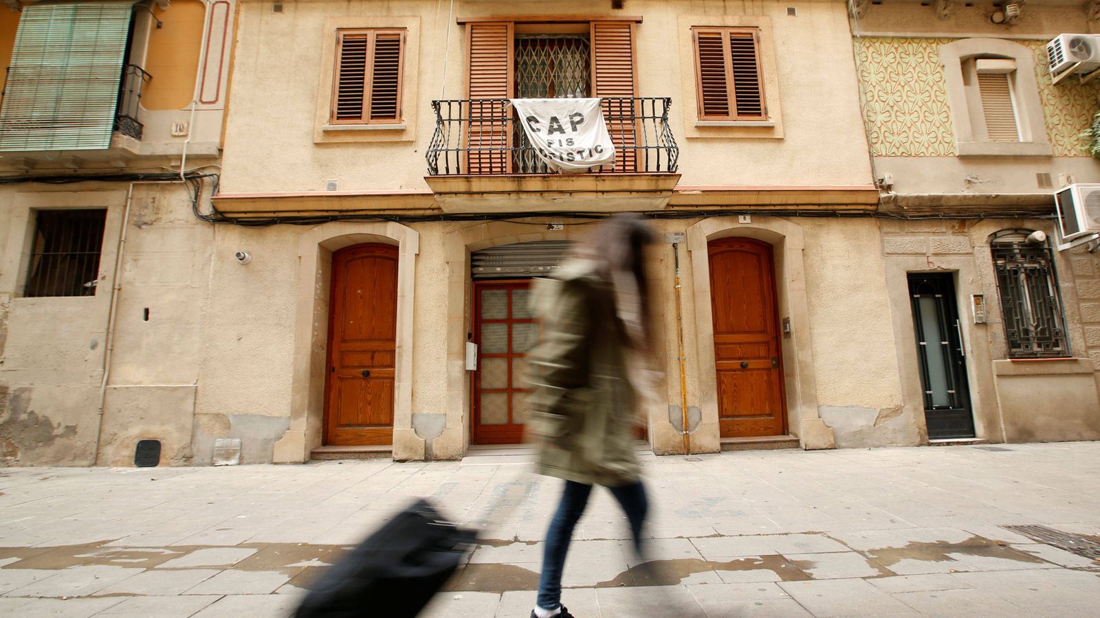 Foto: Una joven sostiene su maleta frente a una pancarta contra Airbnb (Reuters)