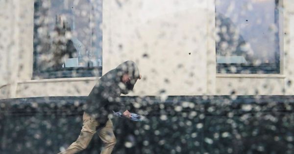 Foto: Varias personas pelean con el viento y la lluvia en San Sebastián. (EFE)