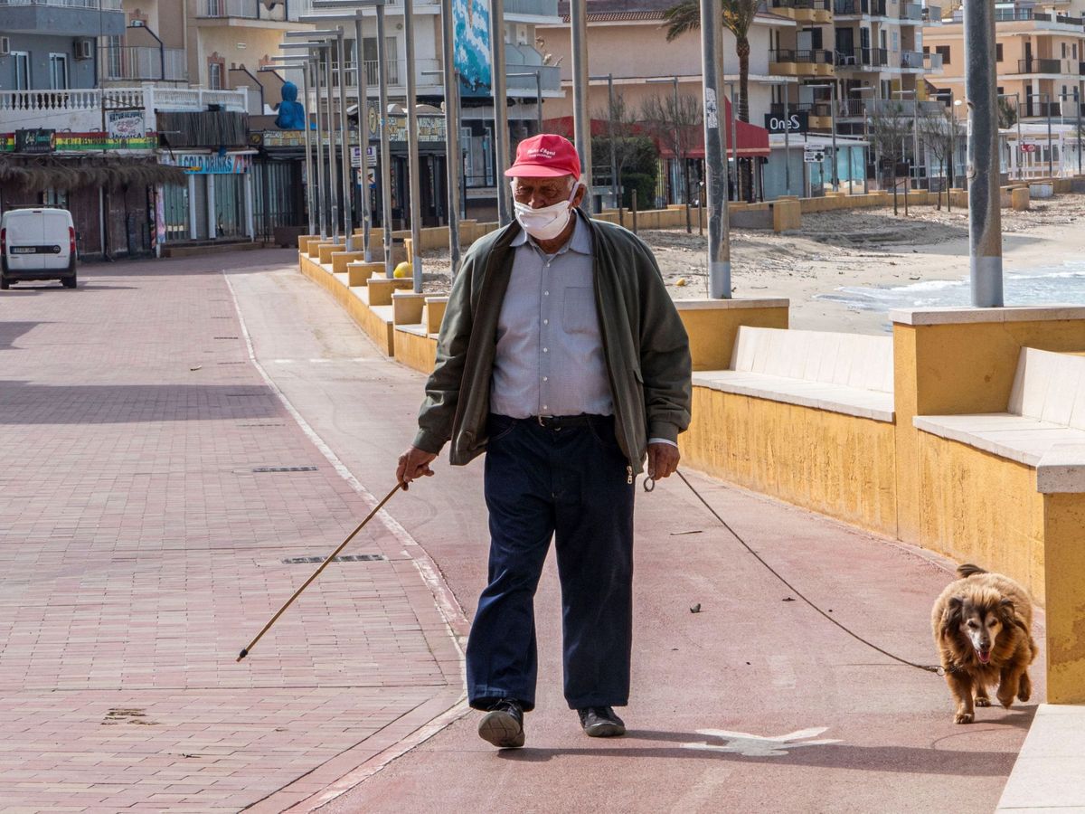 Foto: Un hombre pasea con su perro por la zona turística de Can Picafort. (EFE)