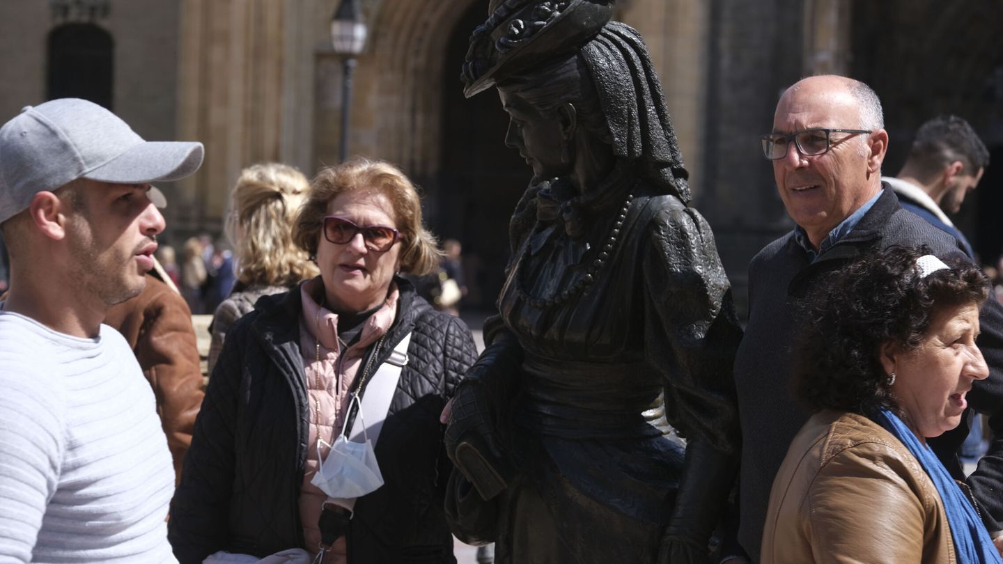 Varios turistas pasan junto a la estatua de La Regenta, en la Plaza de la Catedral de Oviedo. (EFE/Paco Paredes)