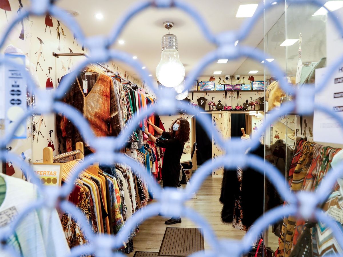 Foto: La propietaria de una tienda de ropa prepara su comercio para poder abrir. (EFE/Juan Herrero)