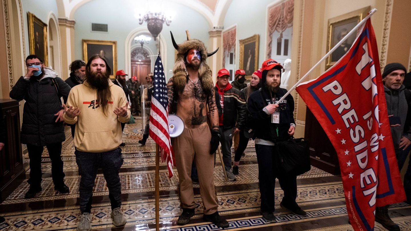 Jacob Albert Chansley (con los cuernos), un miembro del movimiento de teorías de la conspiración QAnon conocido como Jake Angeli O 'Yellowstone Wolf', mientras camina junto a otros simpatizantes de Trump por los pasillos del Capitolio en Washington el pasado 6 de enero (EFE)