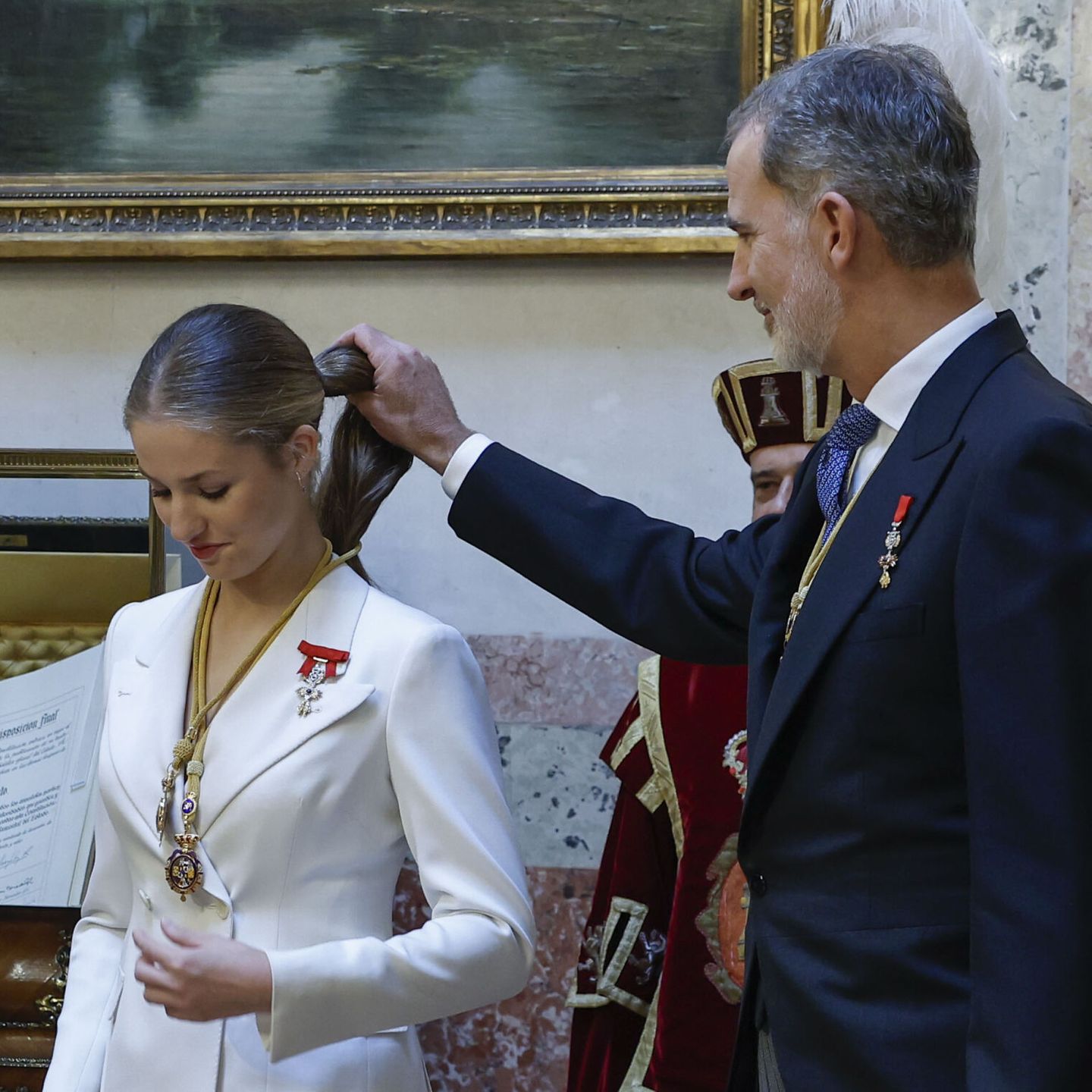 La princesa Leonor es ayudada por su padre, Felipe VI, tras serle impuestas las medallas del Congreso y Senado. (EFE)