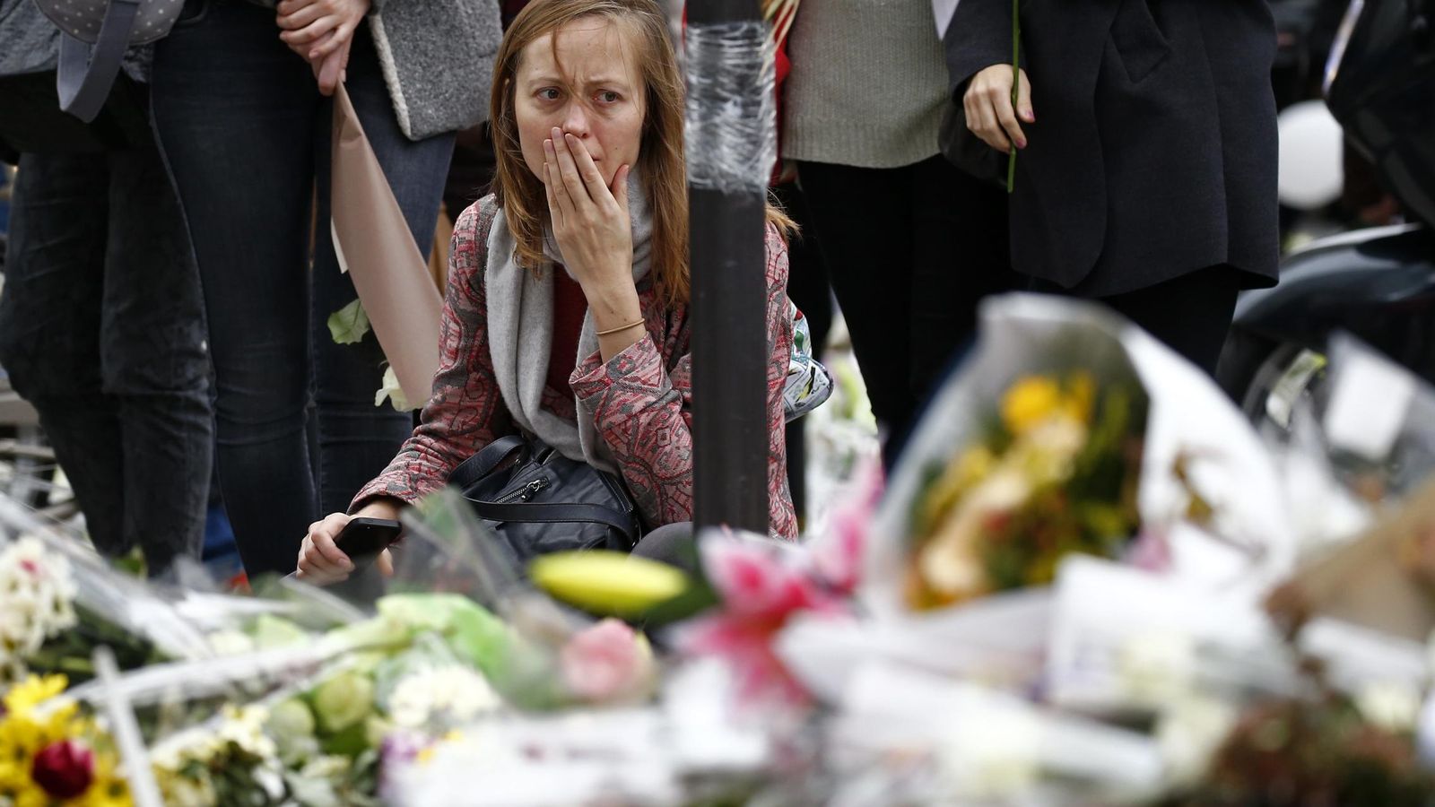 Foto: Una mujer reacciona frente a los monumentos de flores que se han creado alrededor de los lugares donde se produjo la tragedia. (Reuters)