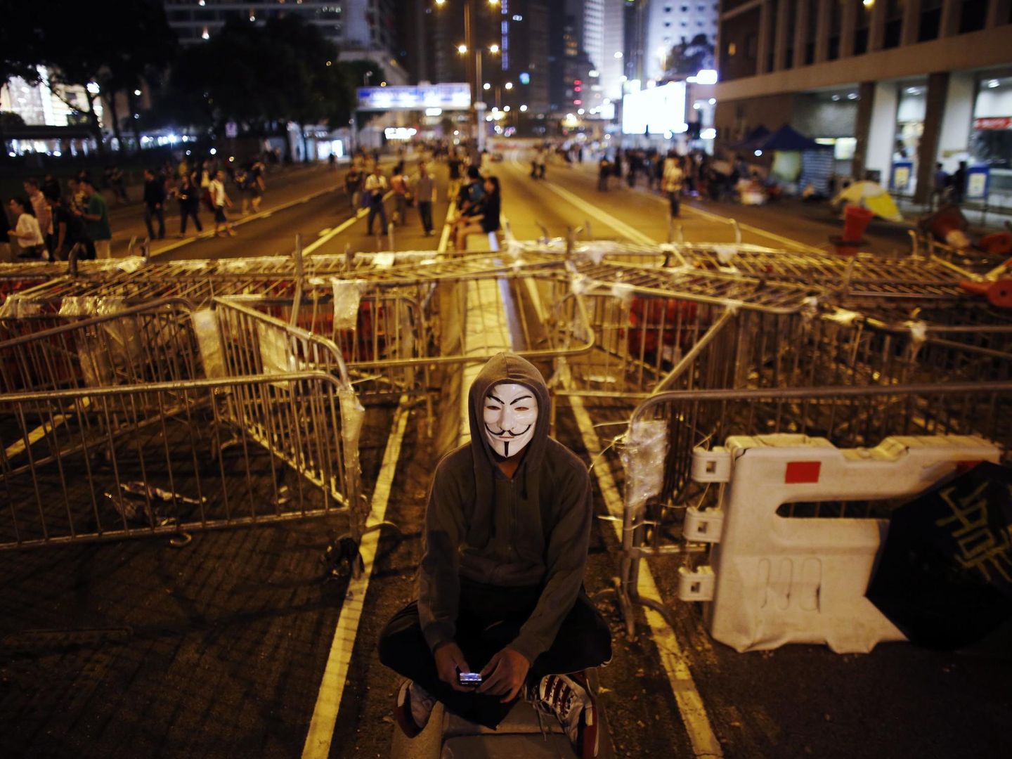 Un manifestante opositor con una máscara se sienta ante una barricada en el distrito financiero (Reuters).