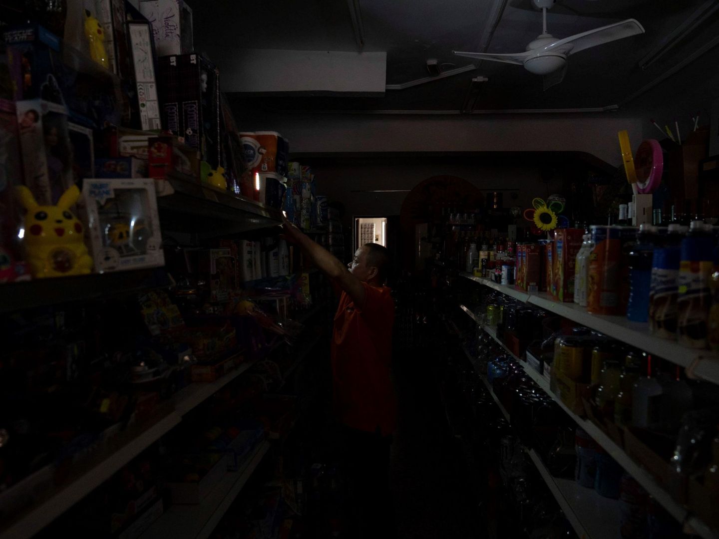 El dueño de una tienda en el centro de Santa Cruz coloca luces provisionales mientras espera a que se restablezca el suministro eléctrico en la isla. (EFE)