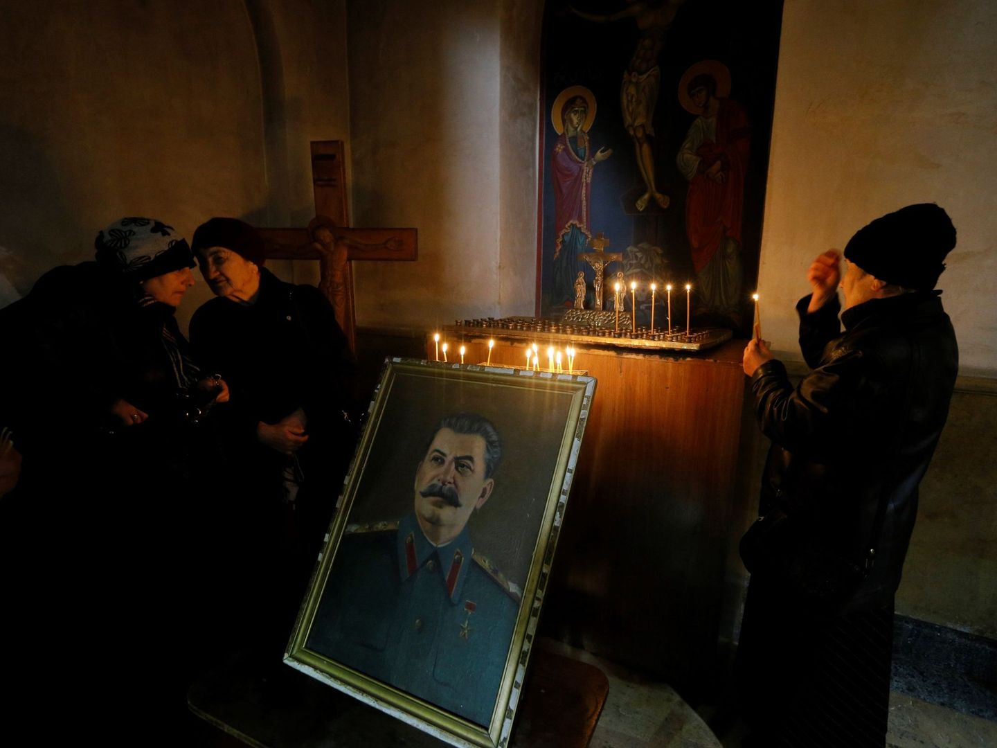 Personas encienden velas junto a un retrato del dictador soviético Iósif Stalin en Gori. (EFE)