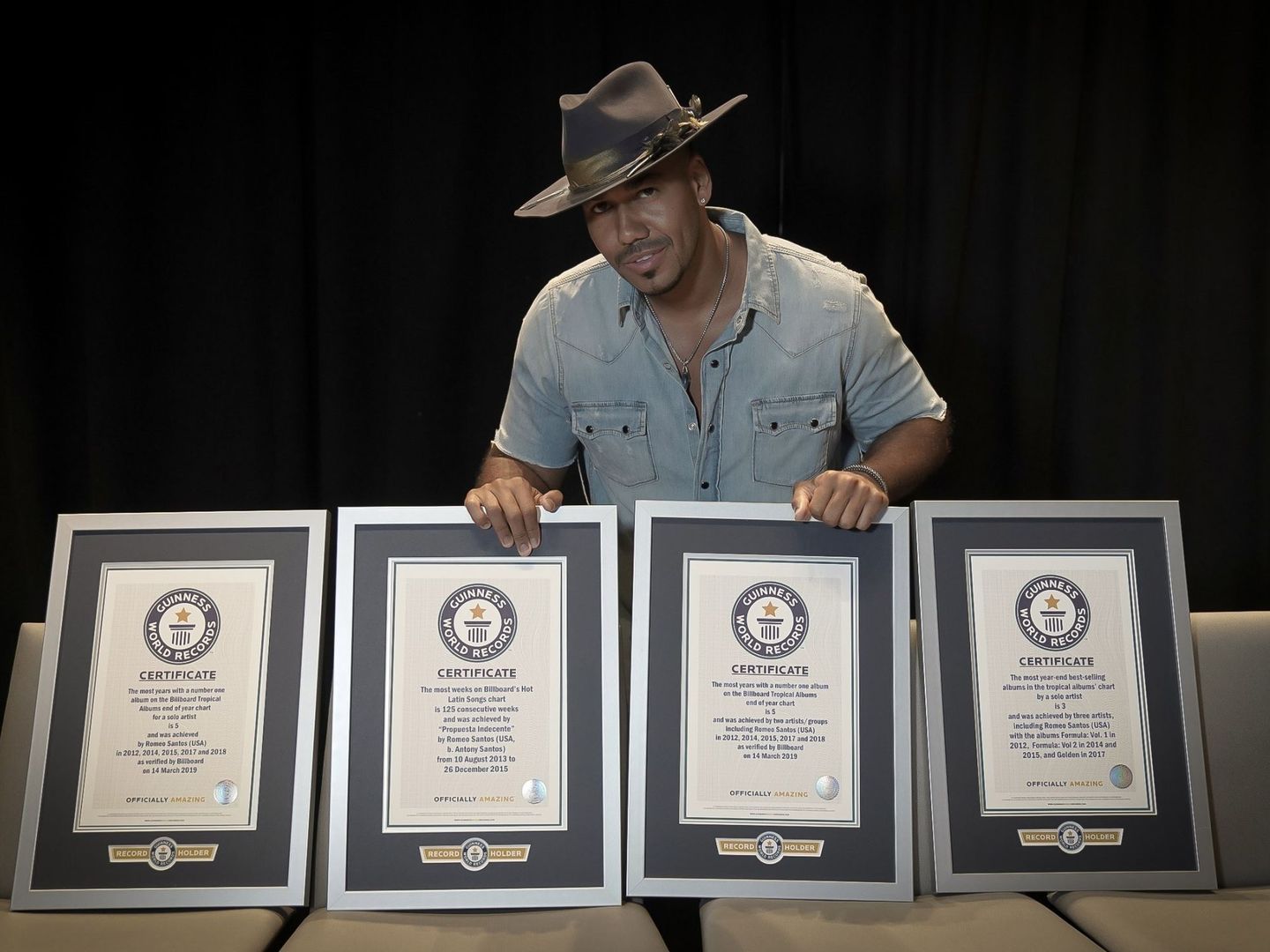 Romeo Santos posando con sus cuatro certificados de récord Guinness. (EFE)