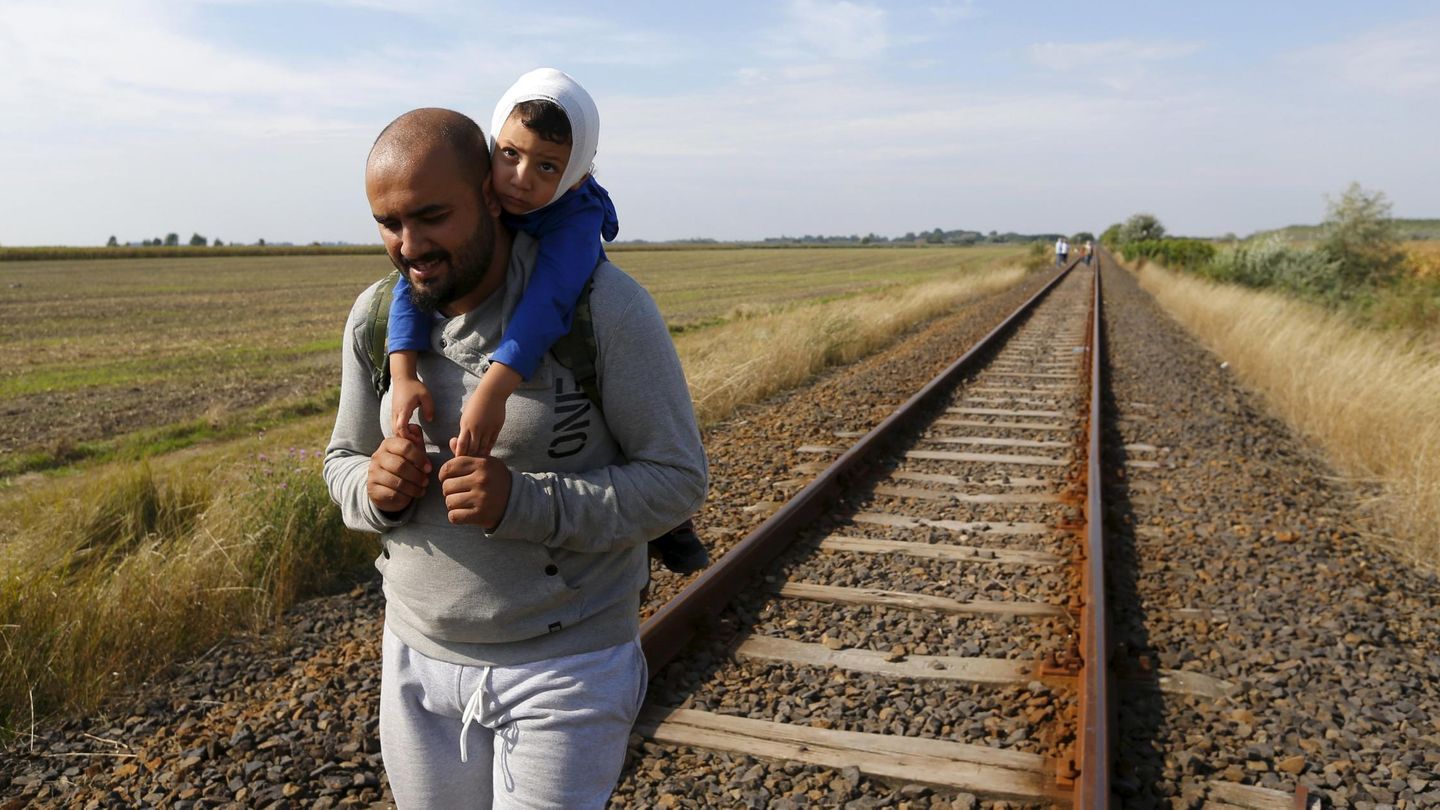 Un inmigrante recorre junto a su hijo la frontera entre Serbia y Hungría. (Reuters)