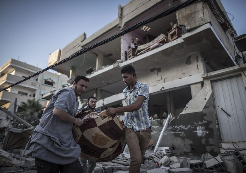 Foto: Varios palestinos rescatan objetos de los escombros en la franja de Gaza. (Efe)