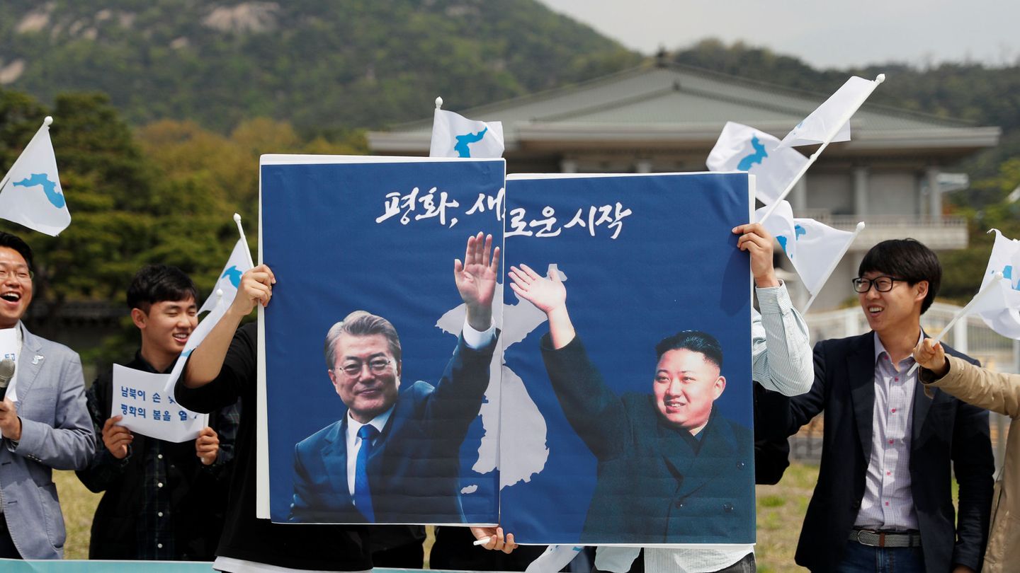 Estudiantes pro-unificación enarbolan posters del presidente surcoreano Moon Jae-in y el norcoreano Kim Jong Un en Seúl, el 26 de abril de 2018. (Reuters)