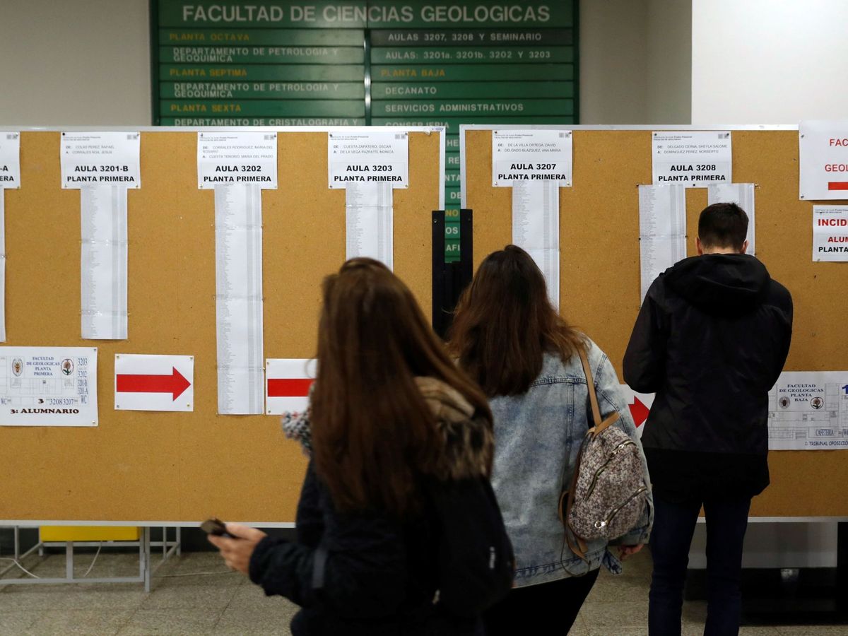 Foto: Varias personas consultan las aulas para realizar el examen de unas oposiciones de Correos. (EFE/Ballesteros)