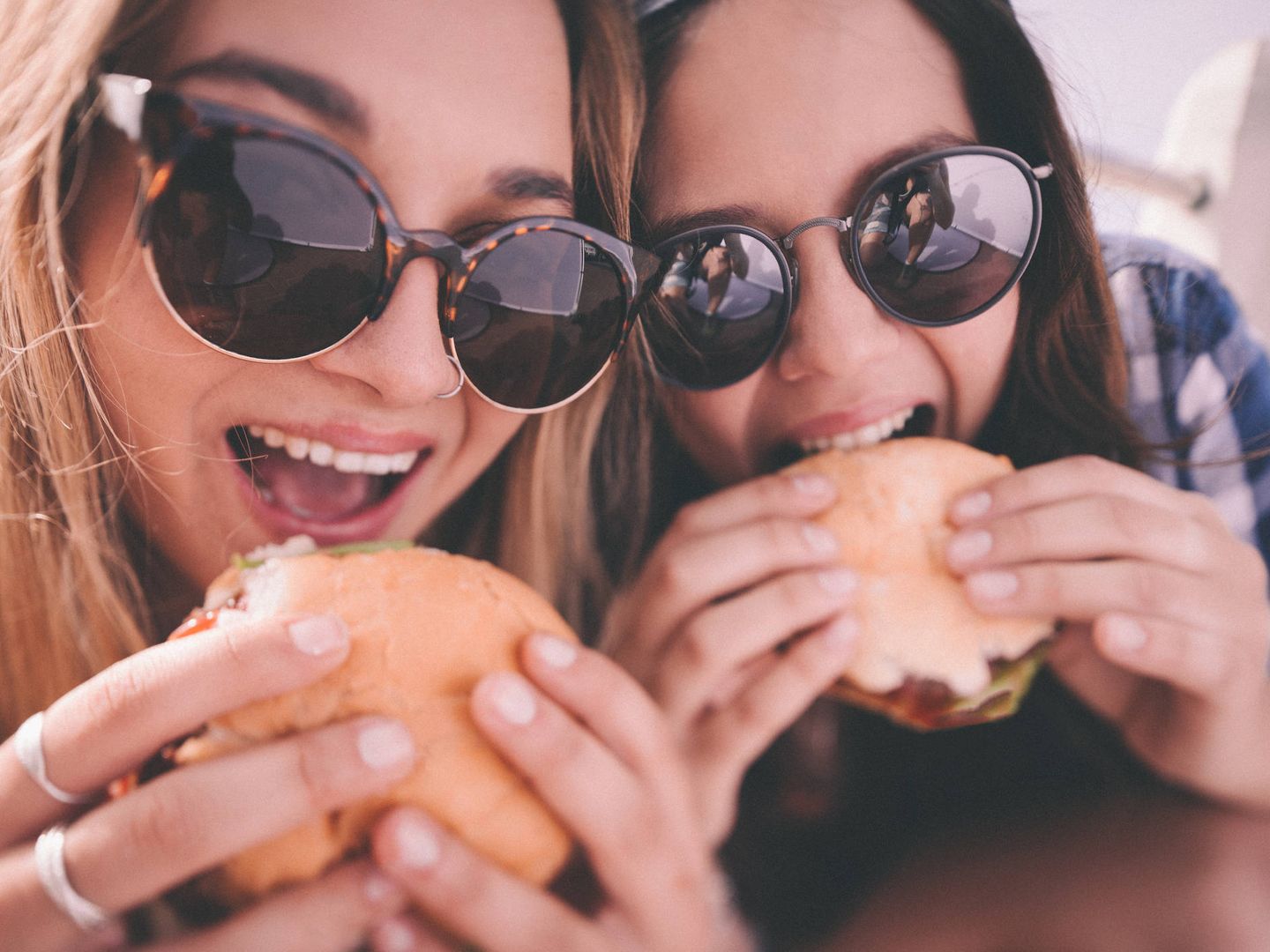 Mejores amigas adolescentes con sendas hamburguesas.