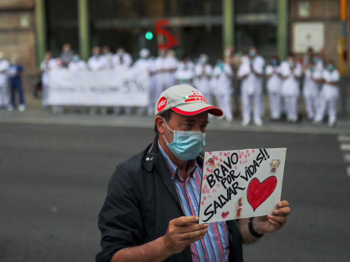 Foto: Un hombre sostiene un cartel en homenaje a los sanitarios durante la crisis del coronavirus en Barcelona. (Reuters)