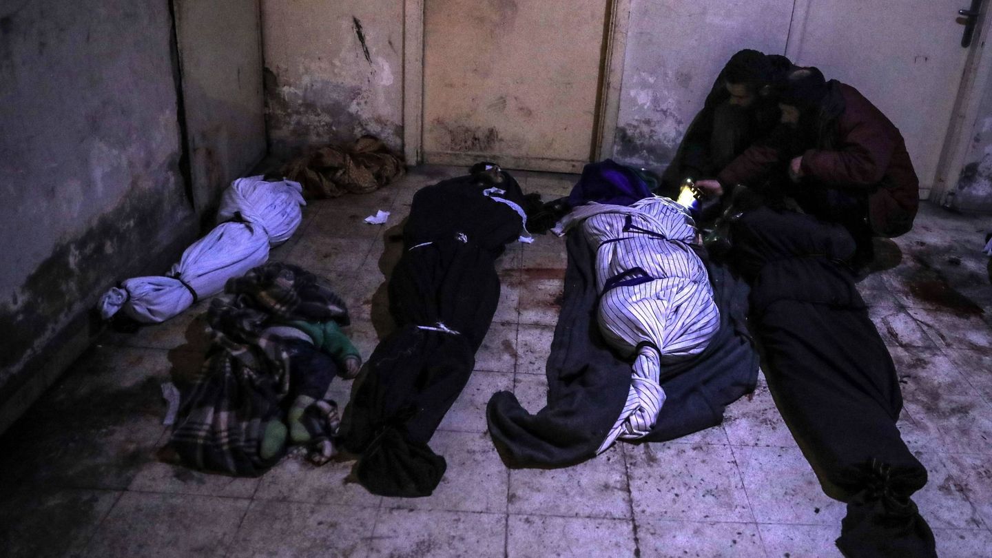 Dos personas trastan de identificar los cadáveres cubiertos con mantas que permanecen en una morgue de Duma, Guta. (EFE)