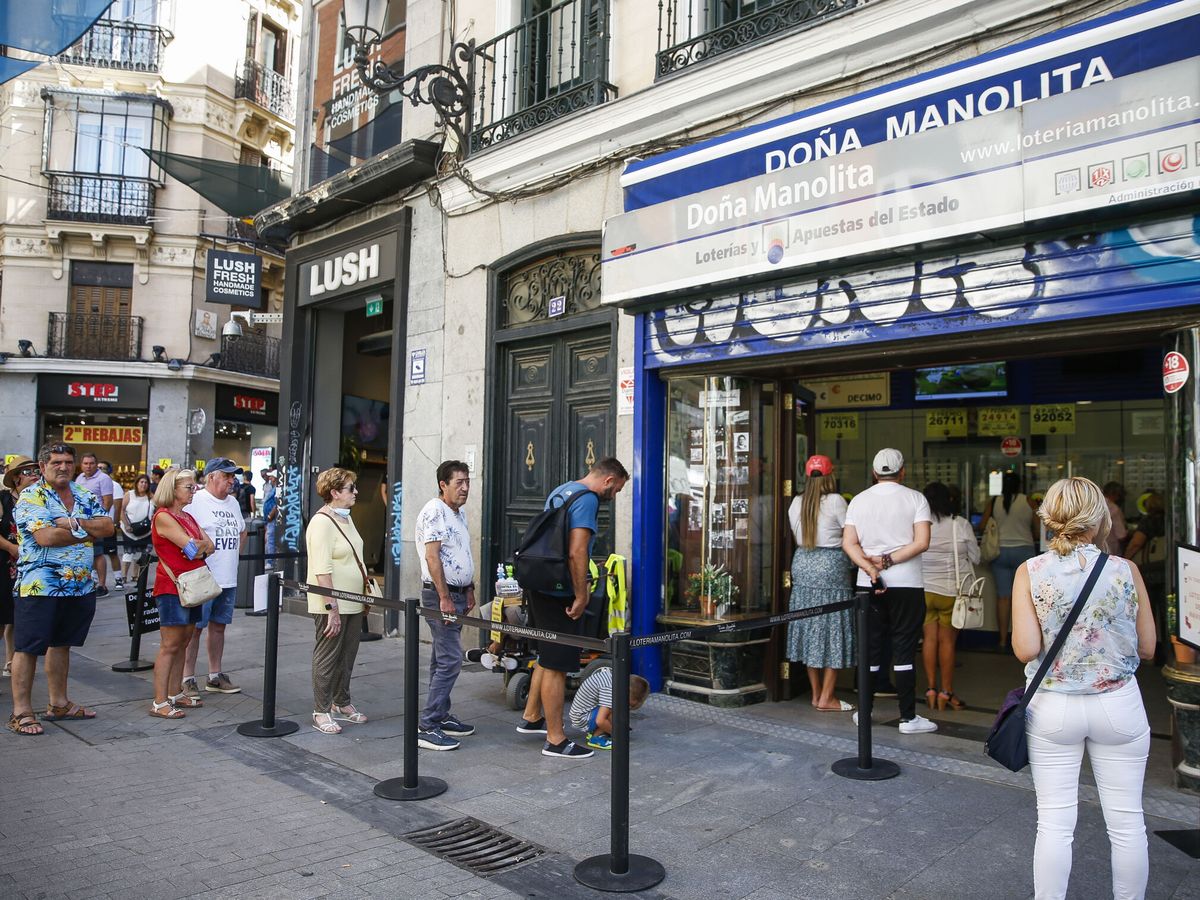 Foto:  Varias personas hacen cola para comprar lotería de Navidad en Doña Manolita en Madrid en pleno agosto. (EFE)