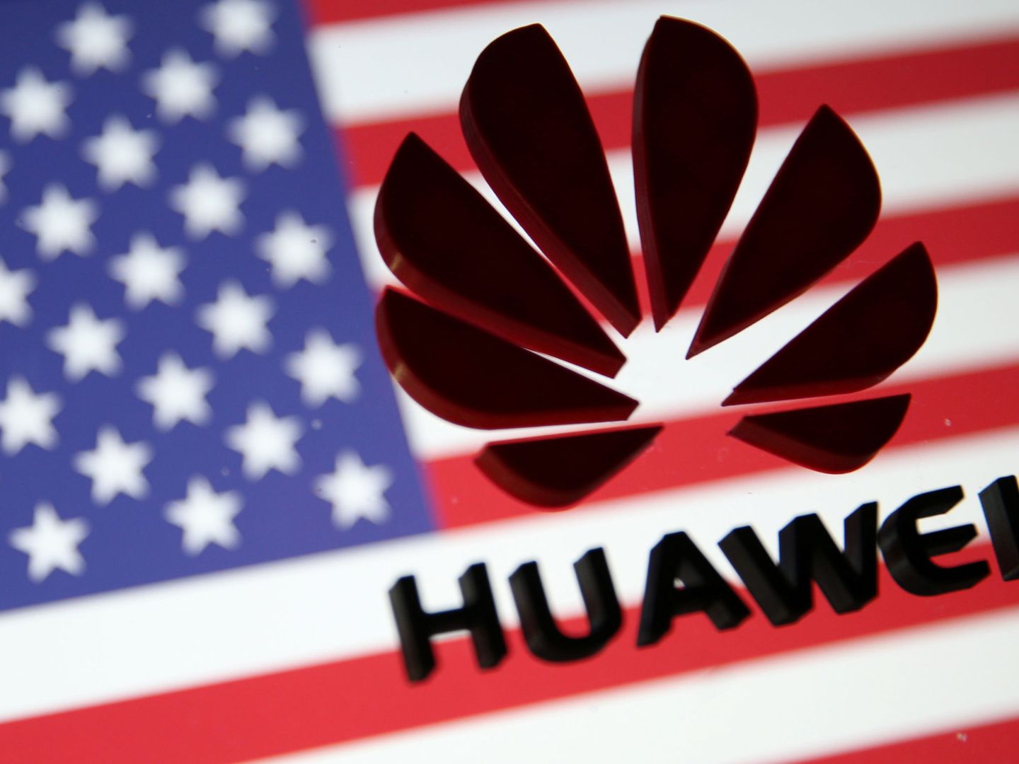 El logo de Huawei frente a una bandera estadounidense. (Reuters)