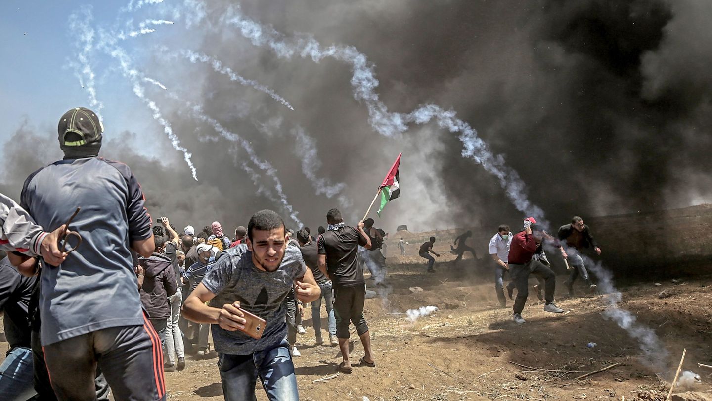 Manifestantes corren para protegerse del gas lacrimógeno lanzado por soldados israelíes durante unas protestas en la frontera de Gaza e Israel, el 14 de mayo de 2018 (EFE).