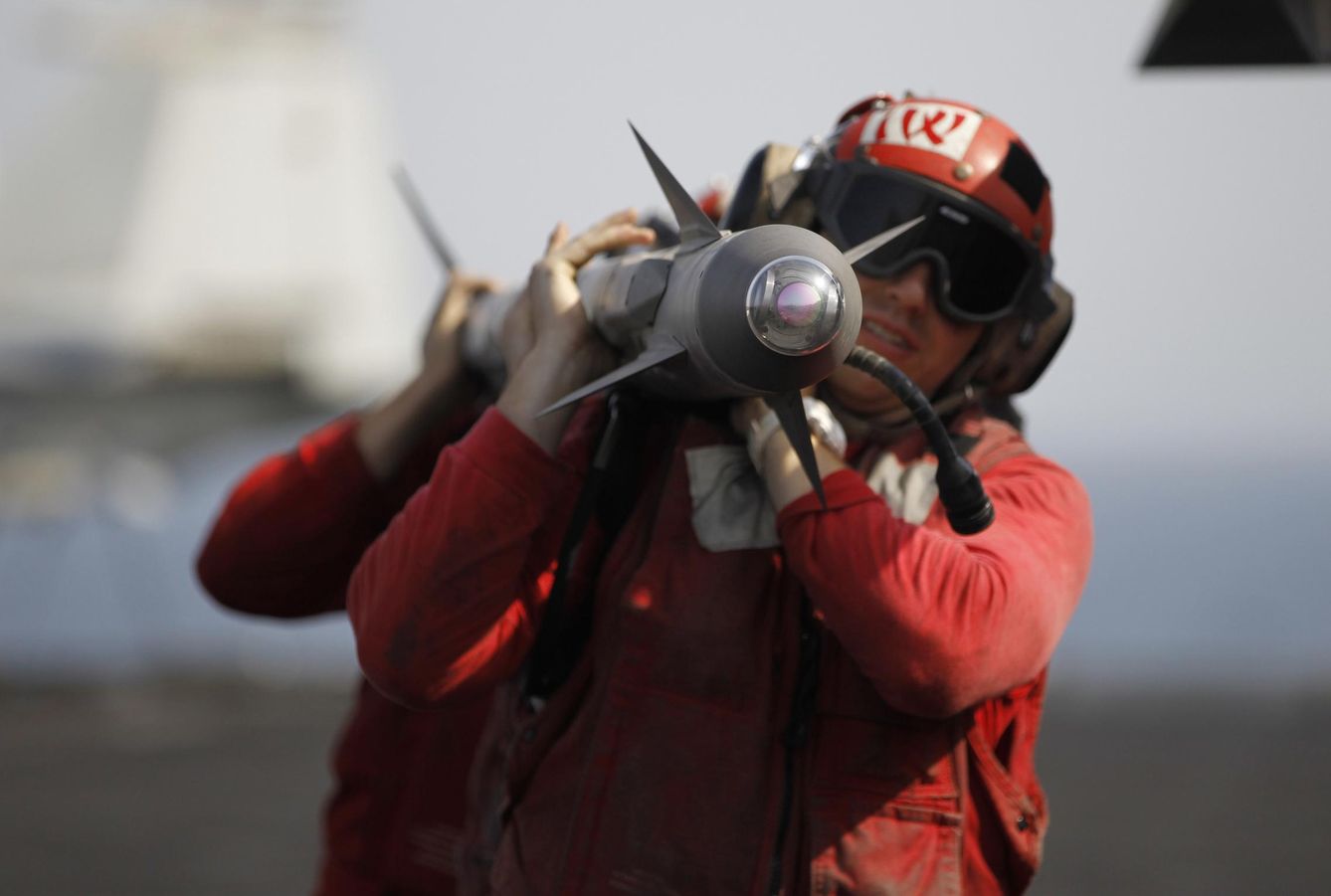 Un grupo de operarios cargan con un proyectil que irá a bordo de un F/A-18. (Reuters)