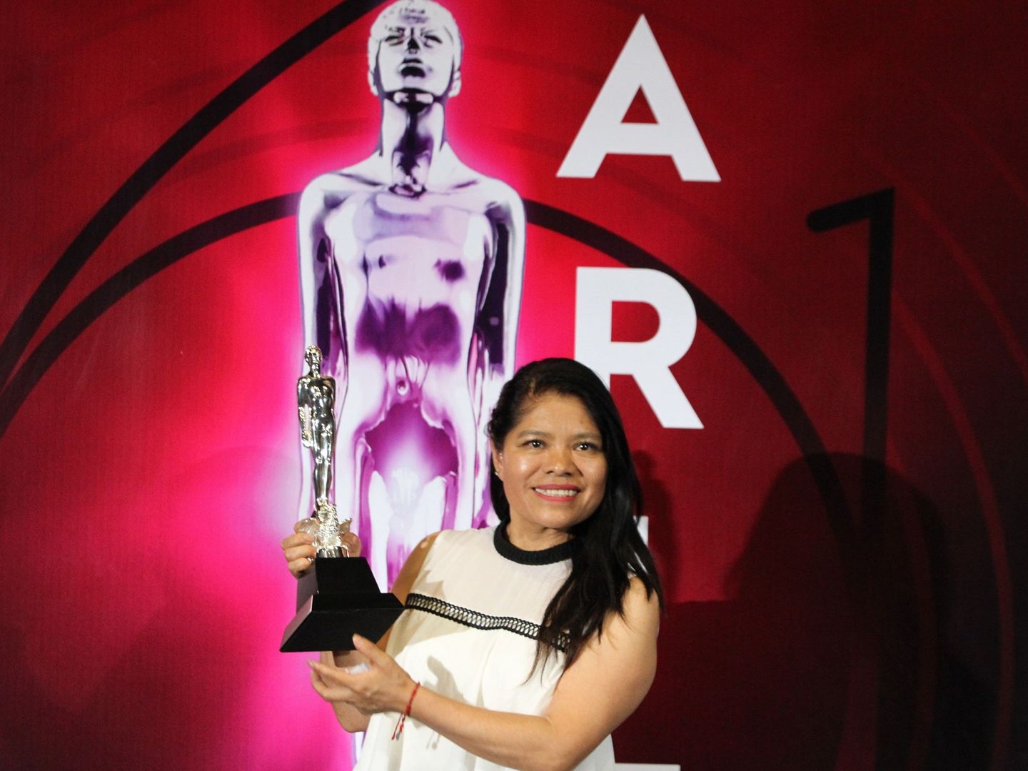 La actriz Marcelina Bautista, en nombre de Alfonso Cuaron, posa con el premio a mejor dirección en la alfombra roja durante la 61 edición de los Premios Ariel que otorga la Academia Mexicana