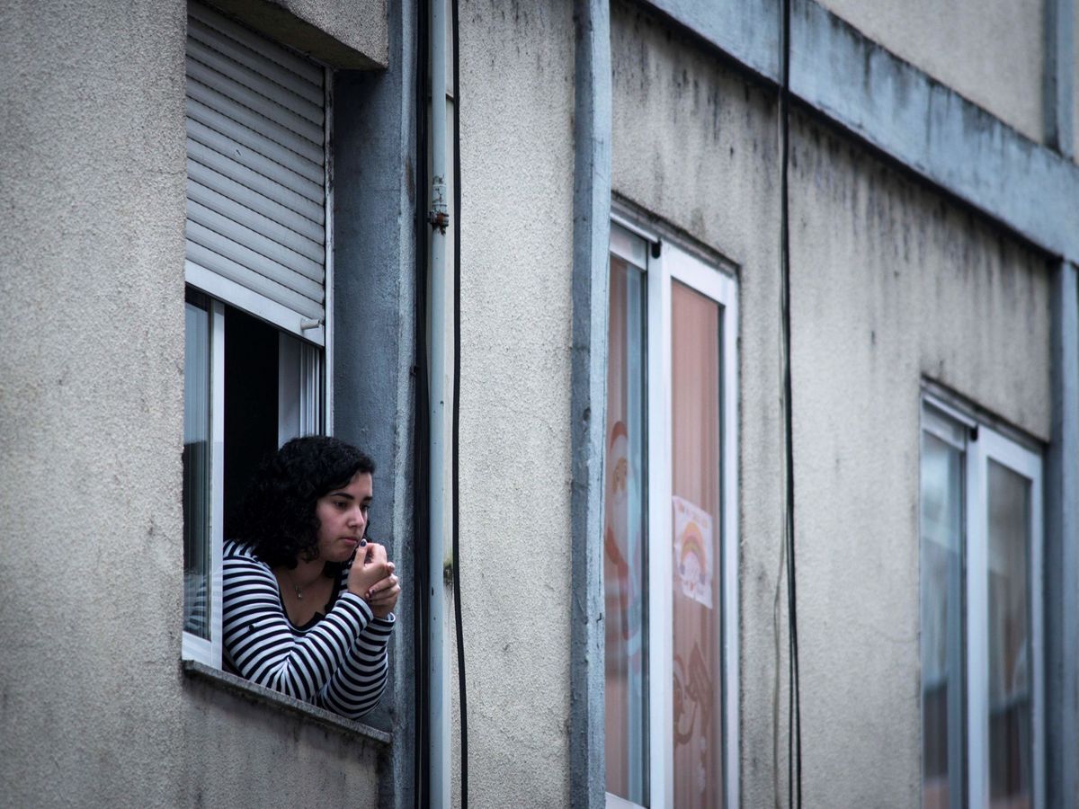Foto: Una mujer jóven, asomada a la ventana de una vivienda. (EFE)