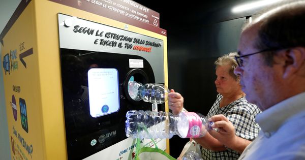 Foto: Dos personas introducen botellas de plástico en la máquina de reciclaje del metro (Reuters/Remo Casilli)