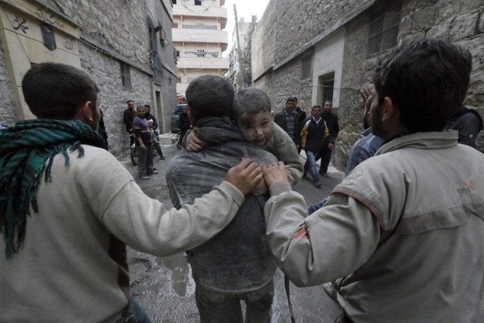 Un hombre socorre a un niño herido en un ataque aéreo en el barrio de Al-Maysar, Alepo (Reuters).