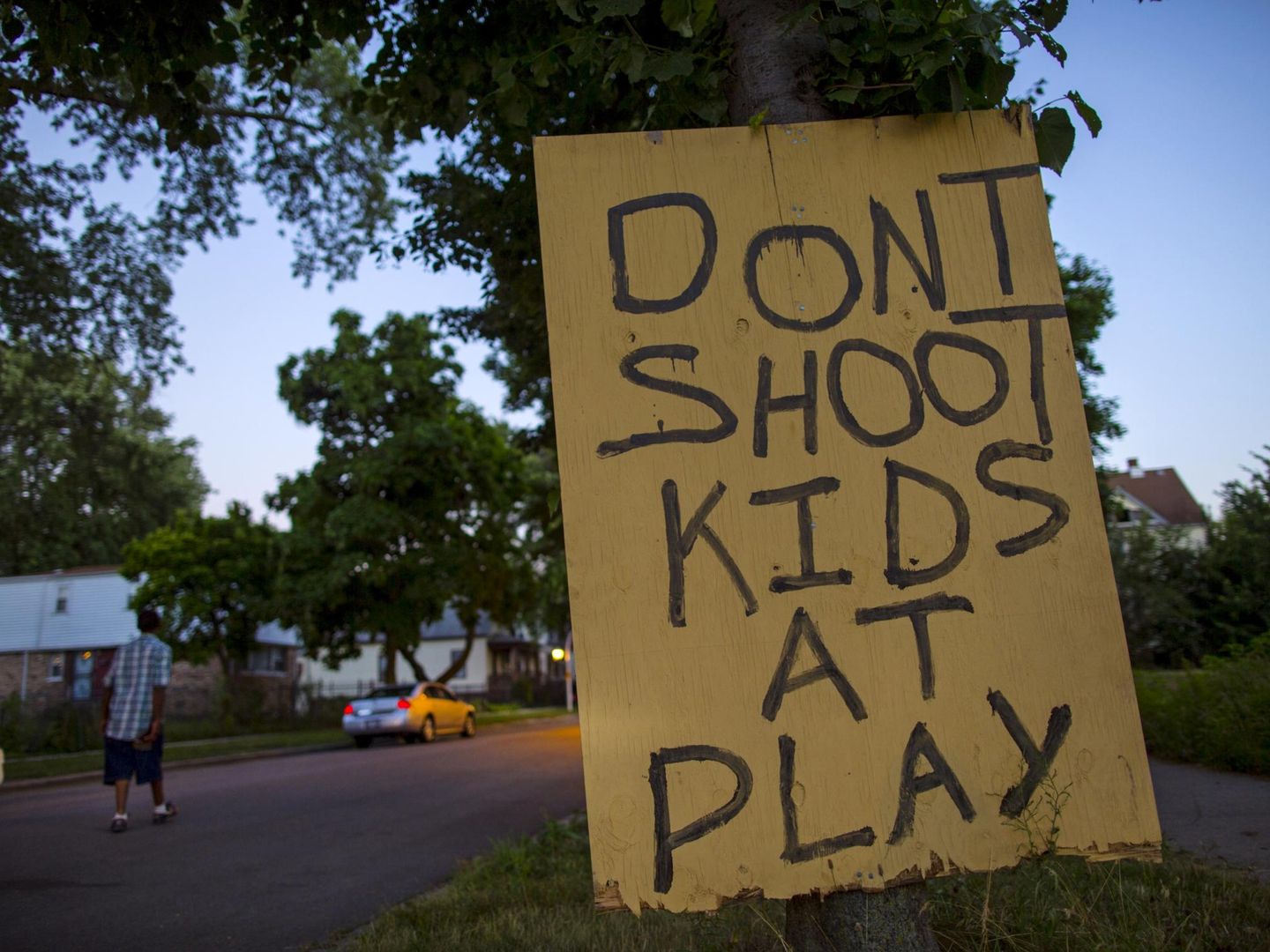 Un hombre camina por Englewood, en Chicago, donde los tiroteos son habituales, tras un cartel que pide no disparar a los niños que estén jugando.  (Reuters)
