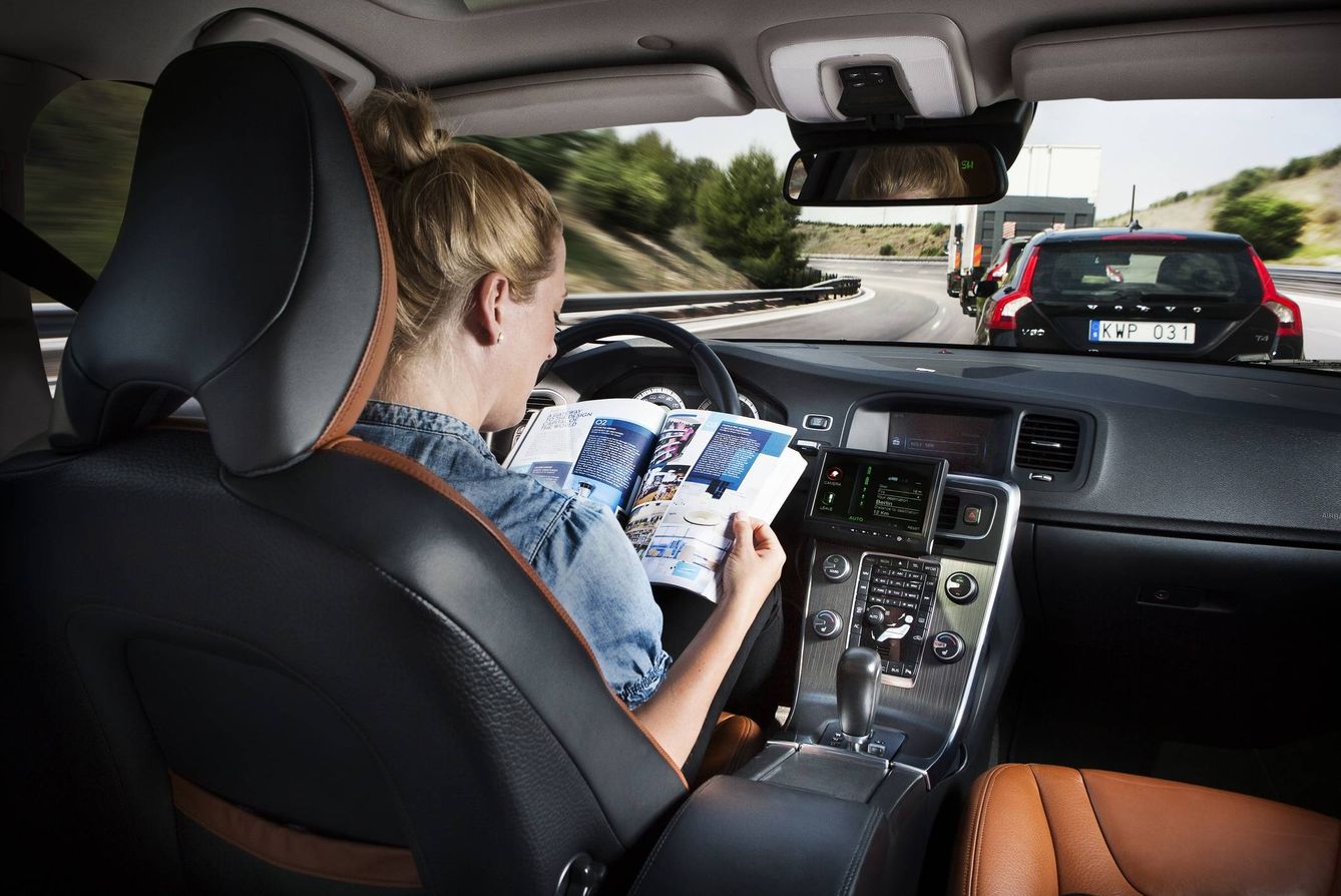 Una mujer lee en el interior de un coche autónomo. 