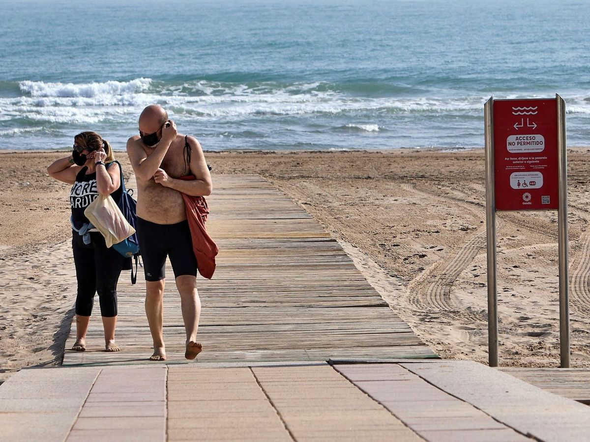 Foto: Dos personas con mascarilla en la playa. (EFE)