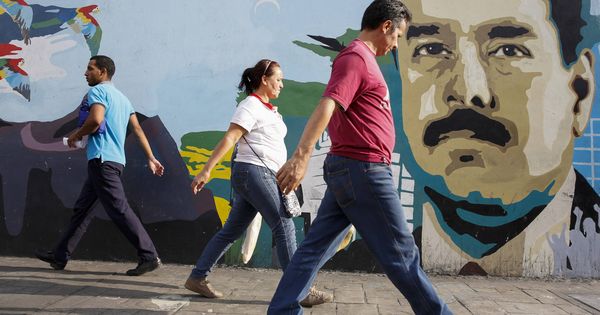 Foto: Varias personas pasan por delante de un mural con la cara del presidente Nicolás Maduro en Caracas, en 2015. (Reuters)