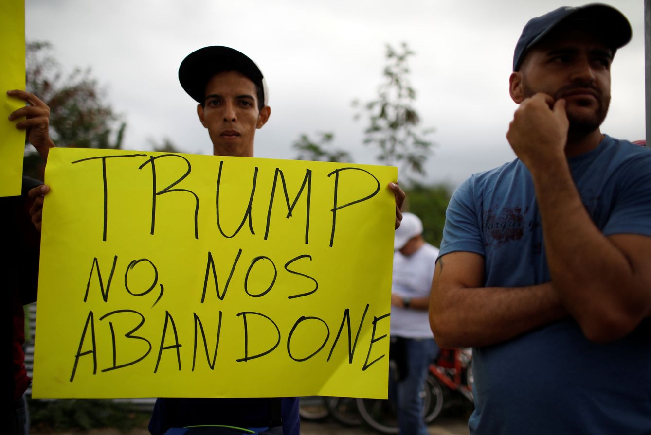 Un venezolano enarbola un cartel pidiendo ayuda a EEUU cerca de un almacen donde se acumula la ayuda humanitaria en la frontera entre Colombia y Venezuela. (Reuters)