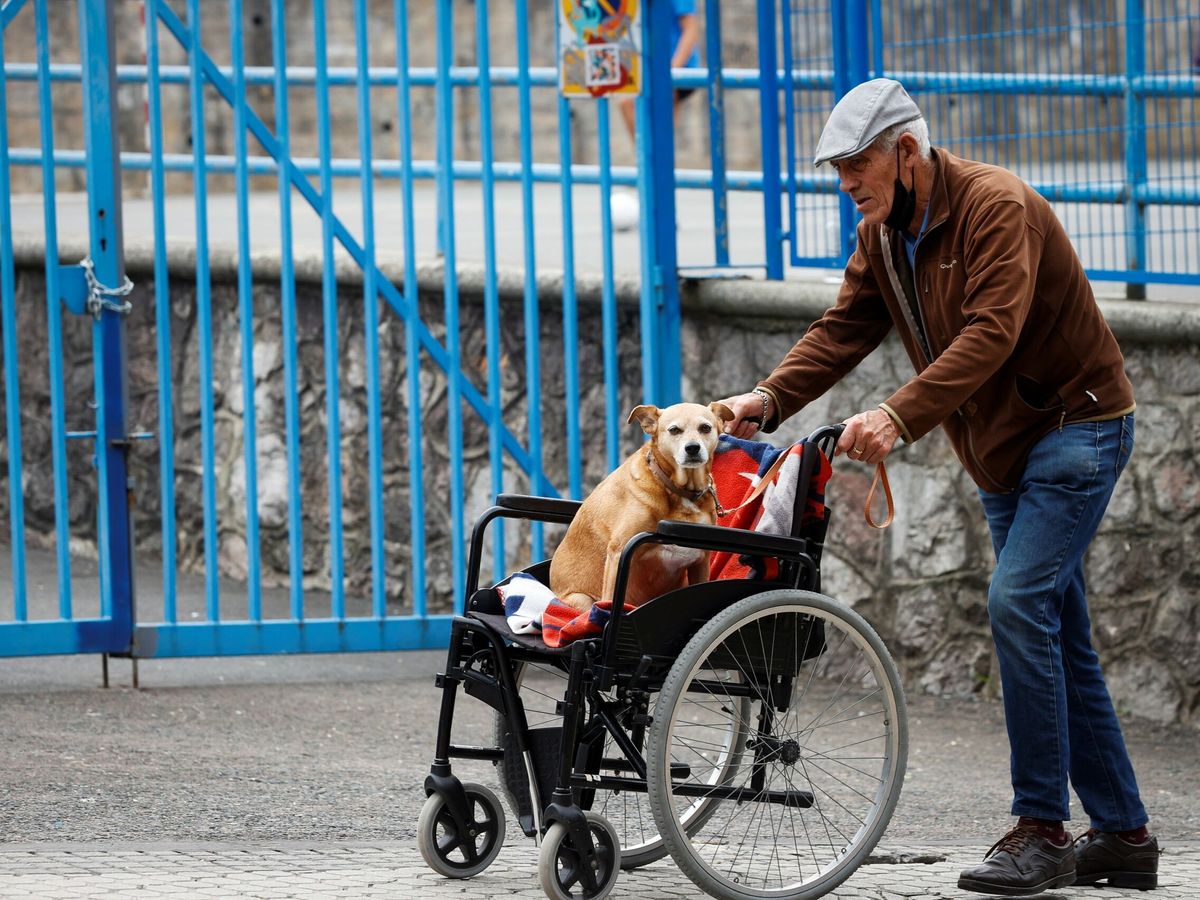 Foto: Un hombre pasea a su perro junto a una residencia de ancianos. (EFE/Javier Etxezarreta)