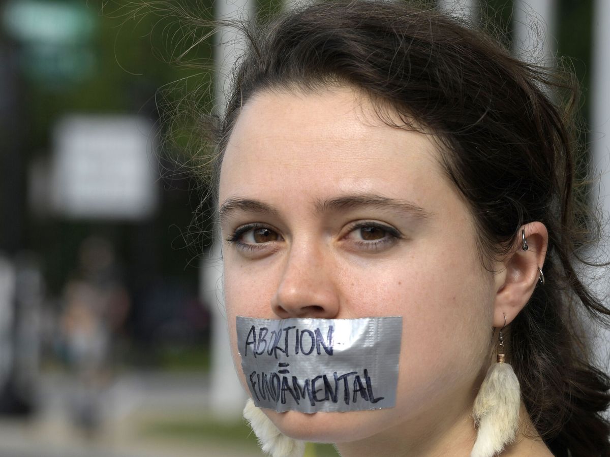 Foto: Una mujer se tapa la boca con una cinta que dice "Aborto es fundamental", durante una manifestación contra el fallo que prohíben el aborto, frente al Tribunal Supremo en Washington (EEUU). (EFE/Lenin Nolly)