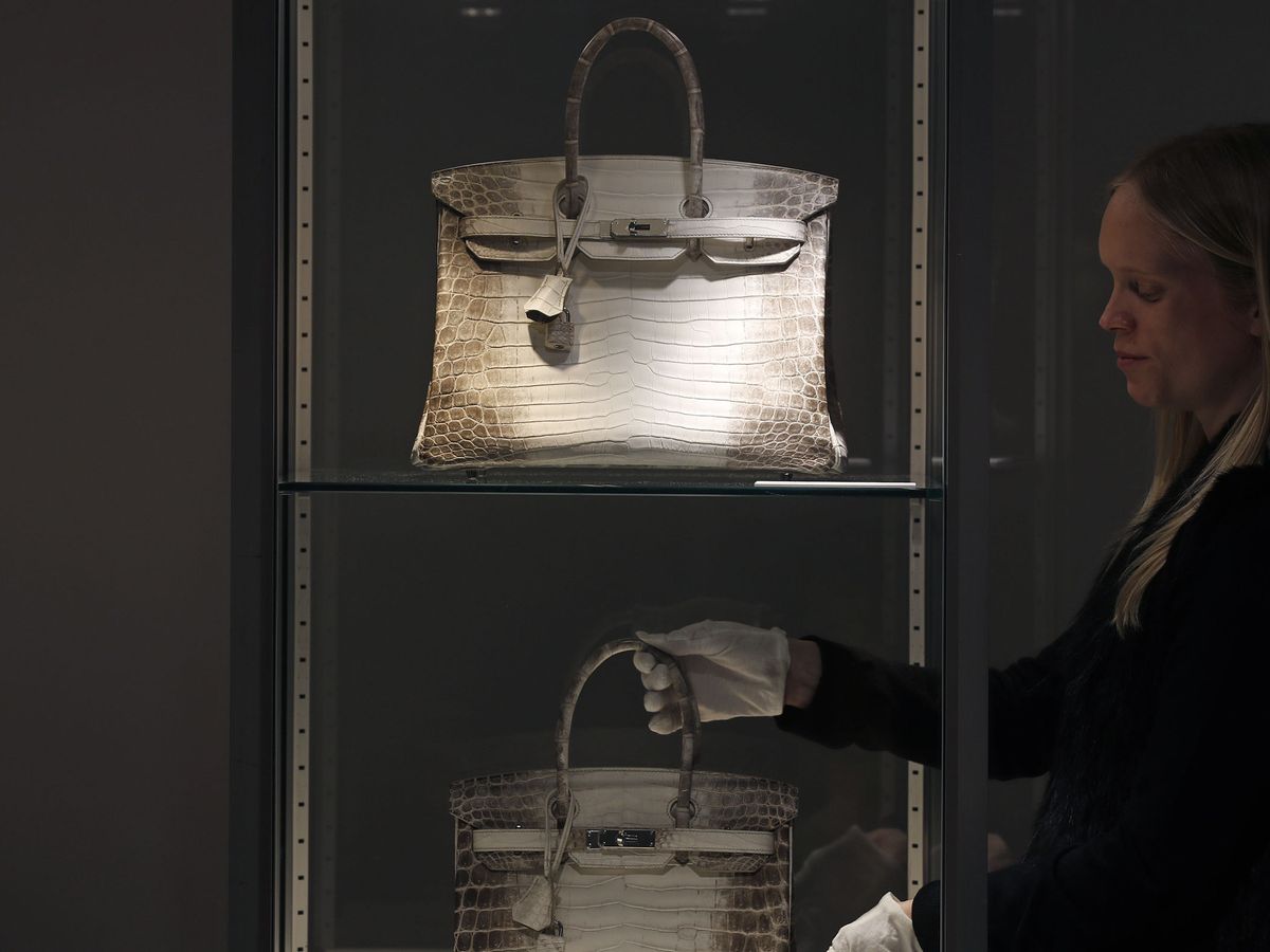 Foto: A staff member poses next to rare hermes handbags during an auction preview at christie's in paris